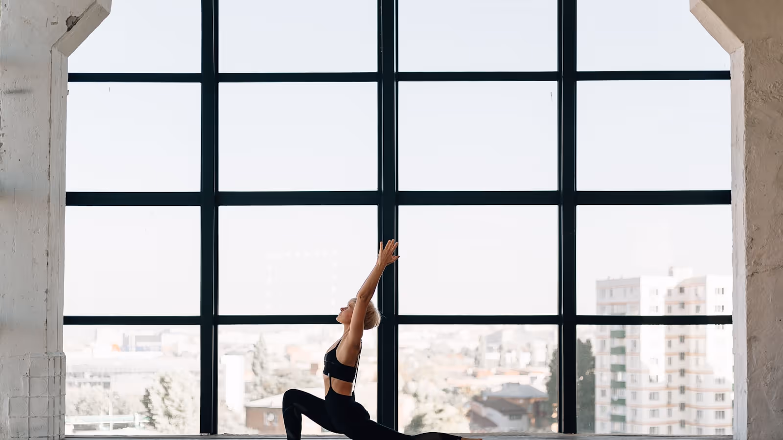 Gros plan sur les jambes d'une personne en posture de guerrier debout sur un tapis de yoga, illustrant l'alignement genou/cheville