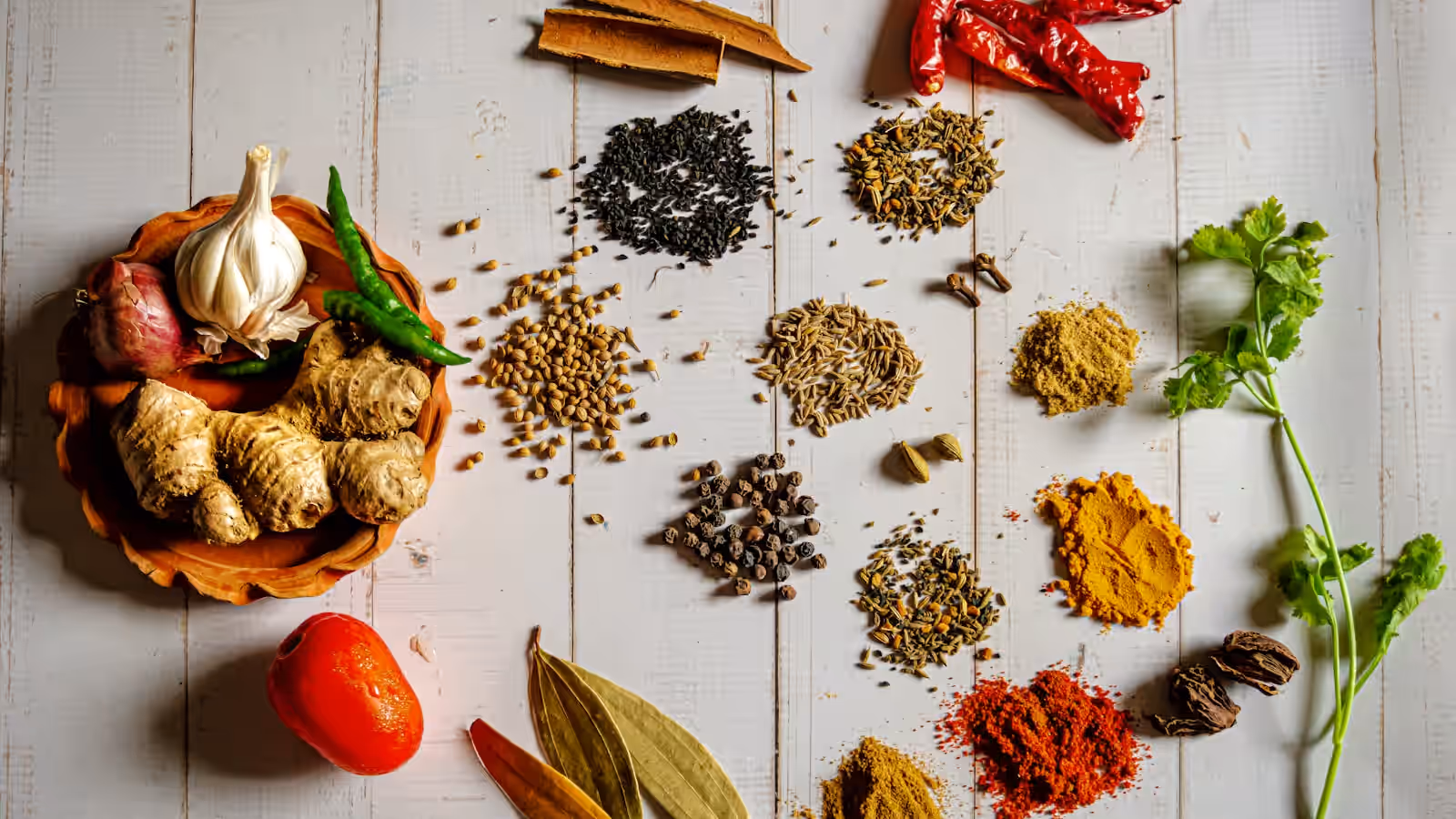 Un bol de nourriture colorée et épicée entouré d'épices sur une table en bois, dans un style associé à la cuisine ayurvédique