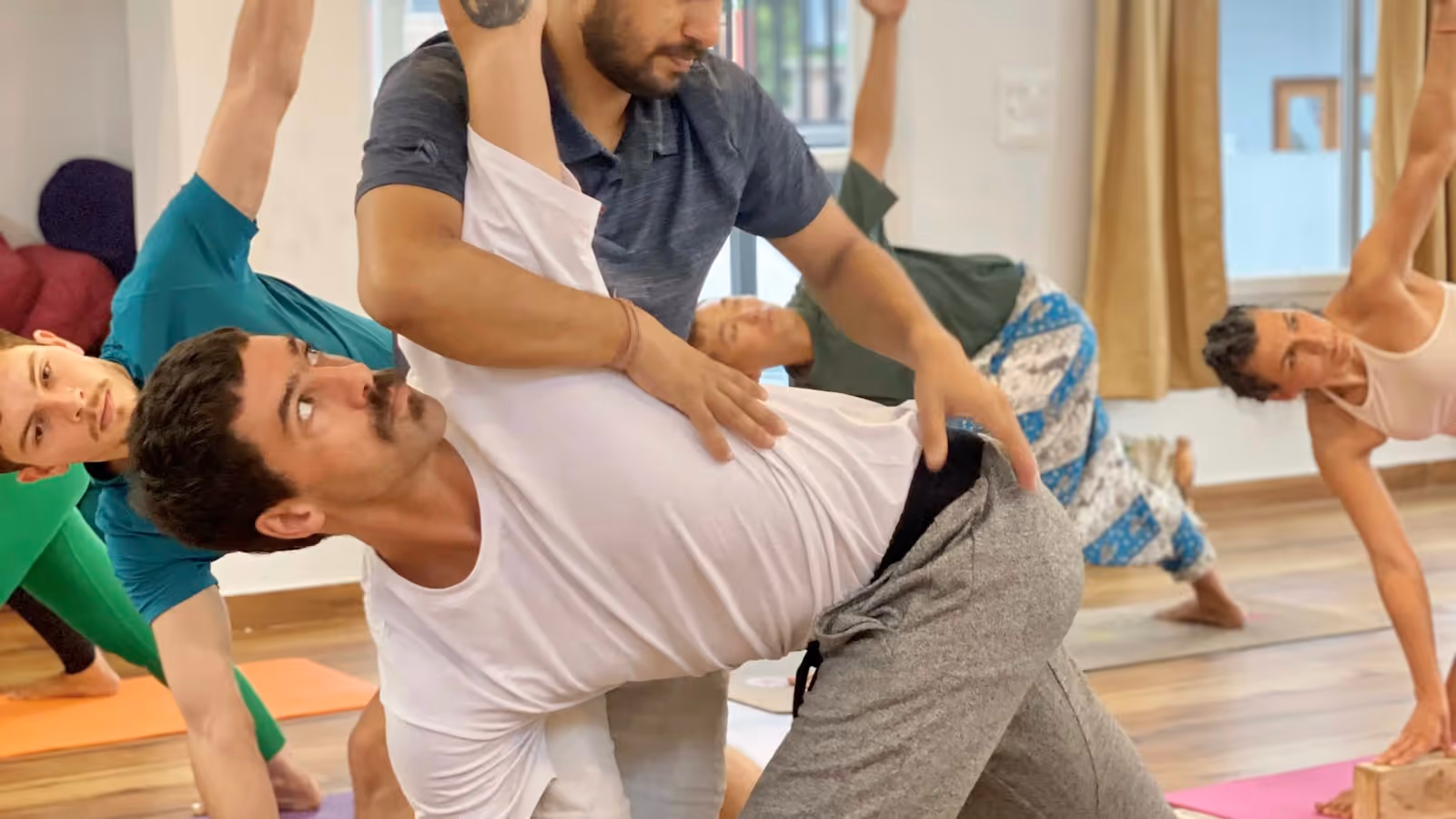 Une pratiquante de yoga ajuste l'alignement de ses bras et de son buste dans une posture debout (photo Sukha Yogashala / Unsplash)